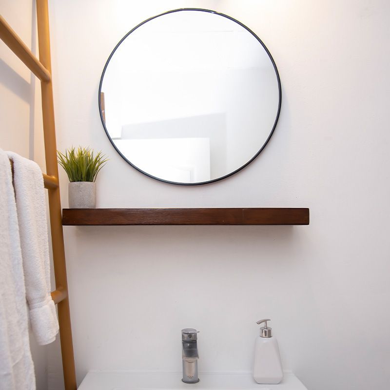 A bathroom with a round mirror and a shelf