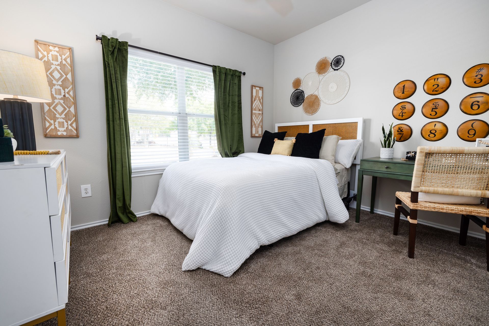 A bedroom with a bed , dresser , chair and window.