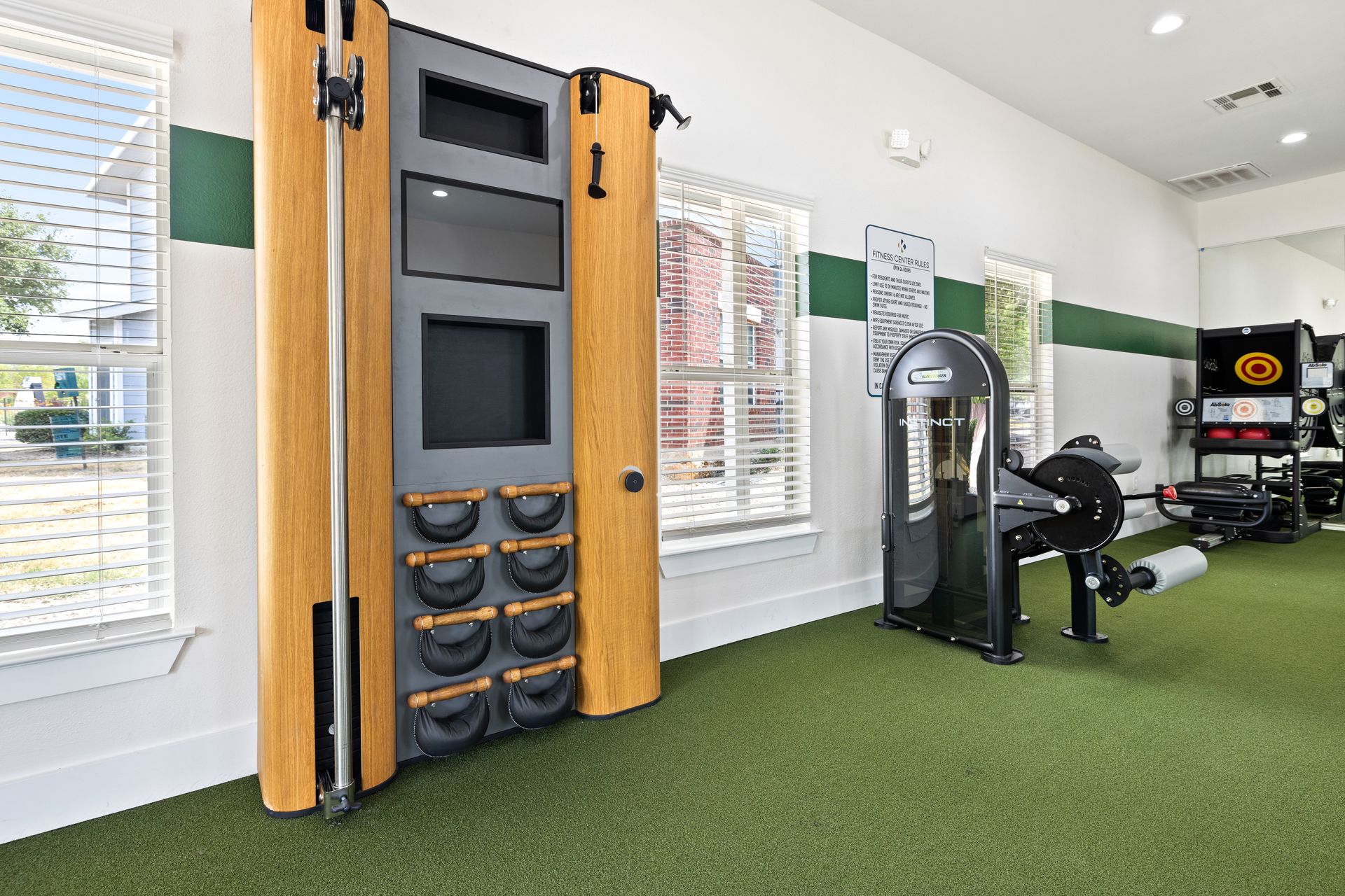 A gym with a lot of exercise equipment and a tv on the wall.
