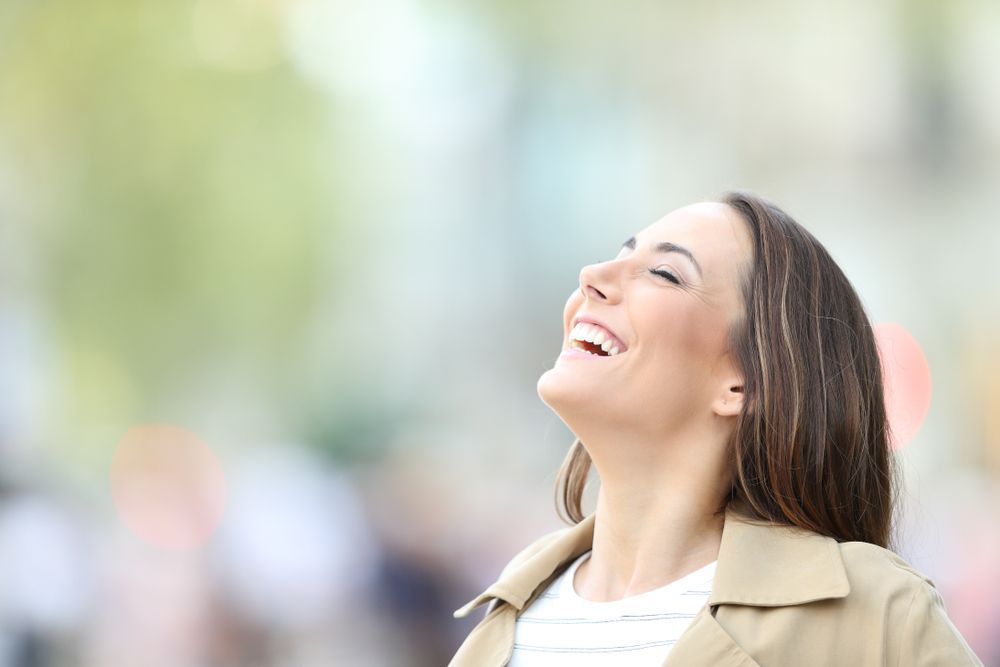 A Woman Is Smiling And Looking Up At The Sky — The Therapists Cairns In Cairns City, QLD