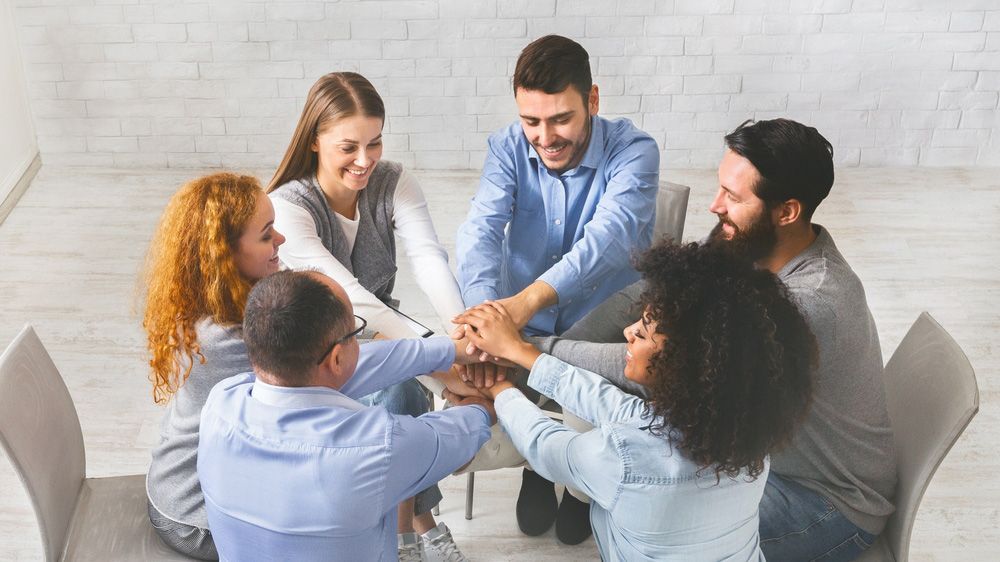 A Group Of People Are Putting Their Hands Together In A Circle — The Therapists Cairns In Cairns City, QLD