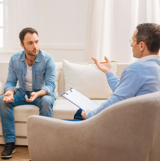 Two Men Are Sitting On A Couch Talking To Each Other — The Therapists Cairns In Cairns City, QLD