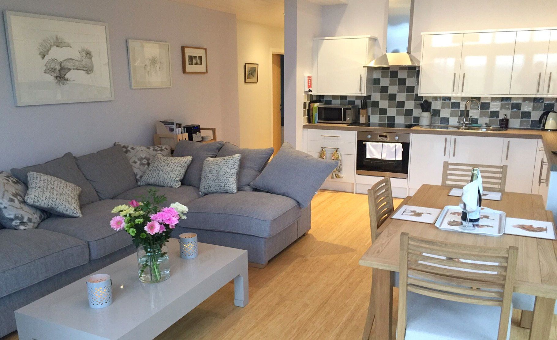 comfy corner sofa in grey with flowers in a vase welcome guests