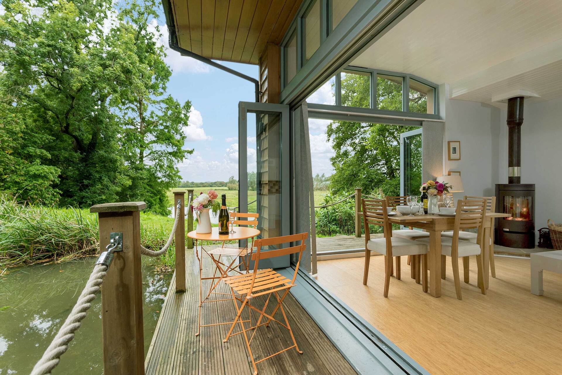 a verandah with seating looking over a small lake in woodland lodge