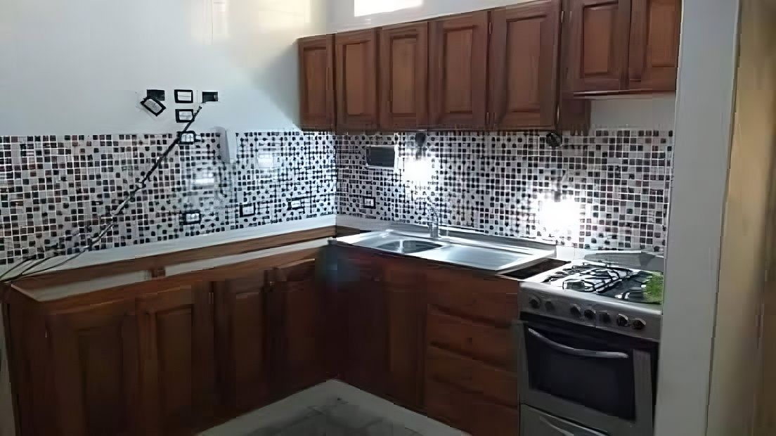 Una cocina con gabinetes de madera, una estufa y un fregadero.