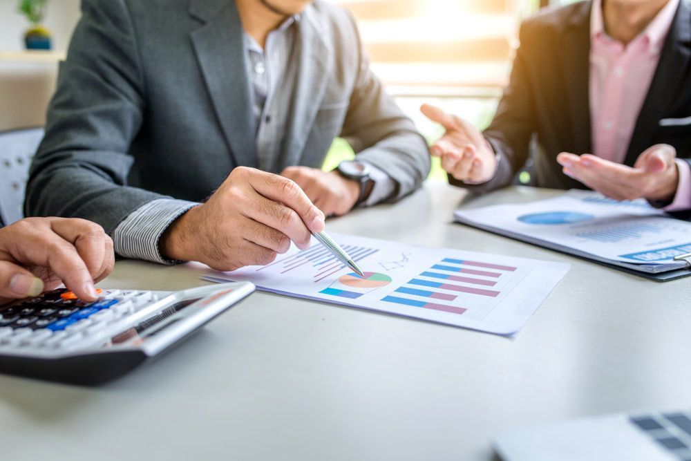 Accountant Sitting At A Table Looking At Papers And A Calculator — Dynamic Accounting Taxation Advisors in Terrigal, NSW