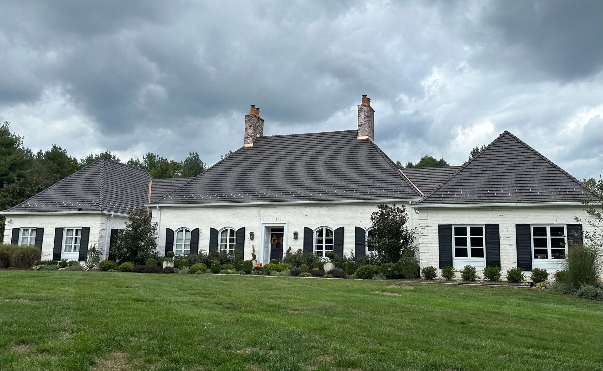 The front upper exterior of a house with blue horizontal siding, white trim, a gabled roof, and a metal porch roof.
