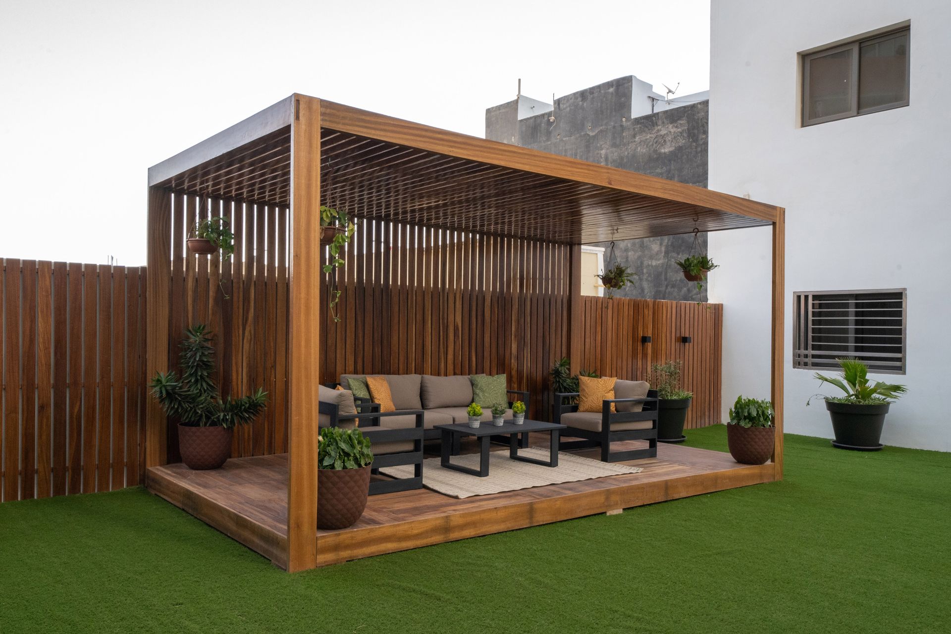 Une pergola en bois avec un canapé et des chaises en dessous dans une cour arrière.