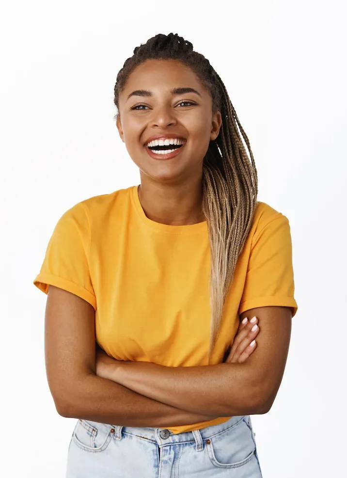 Une femme en chemise jaune sourit avec les bras croisés.