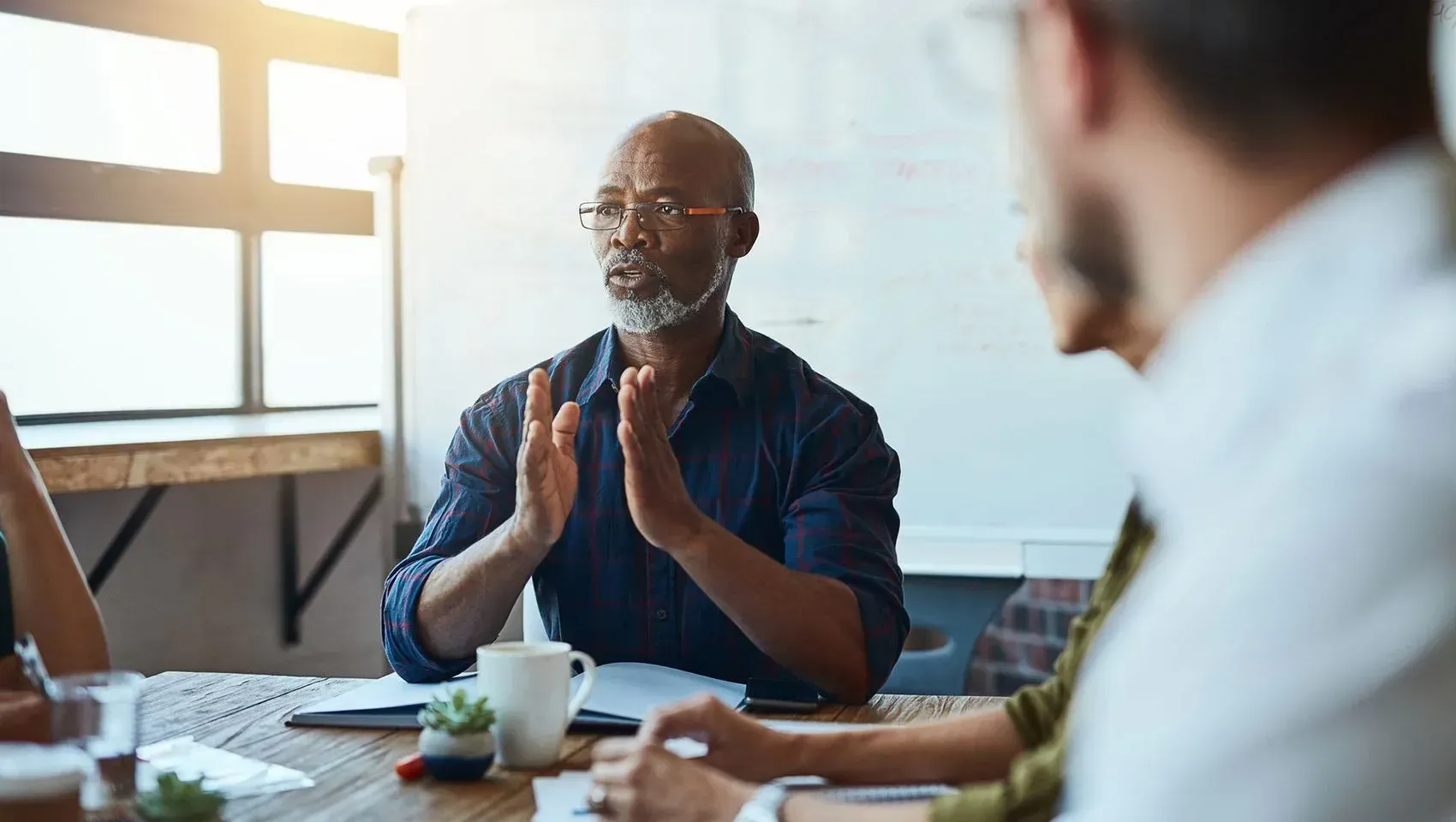 Un homme est assis à une table et parle à un groupe de personnes.