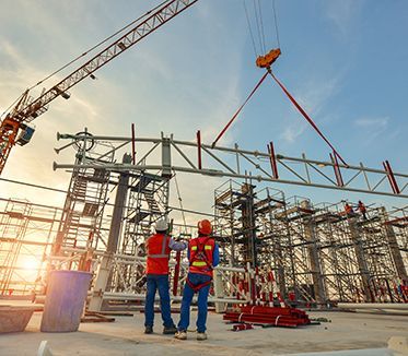 Deux ouvriers du bâtiment se tiennent devant une grue sur un chantier de construction.
