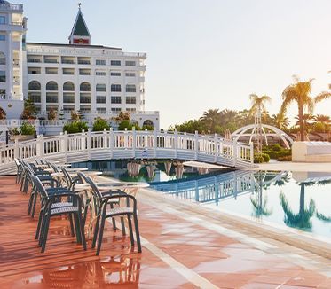 Une rangée de chaises assises à côté d'une piscine devant un grand bâtiment.