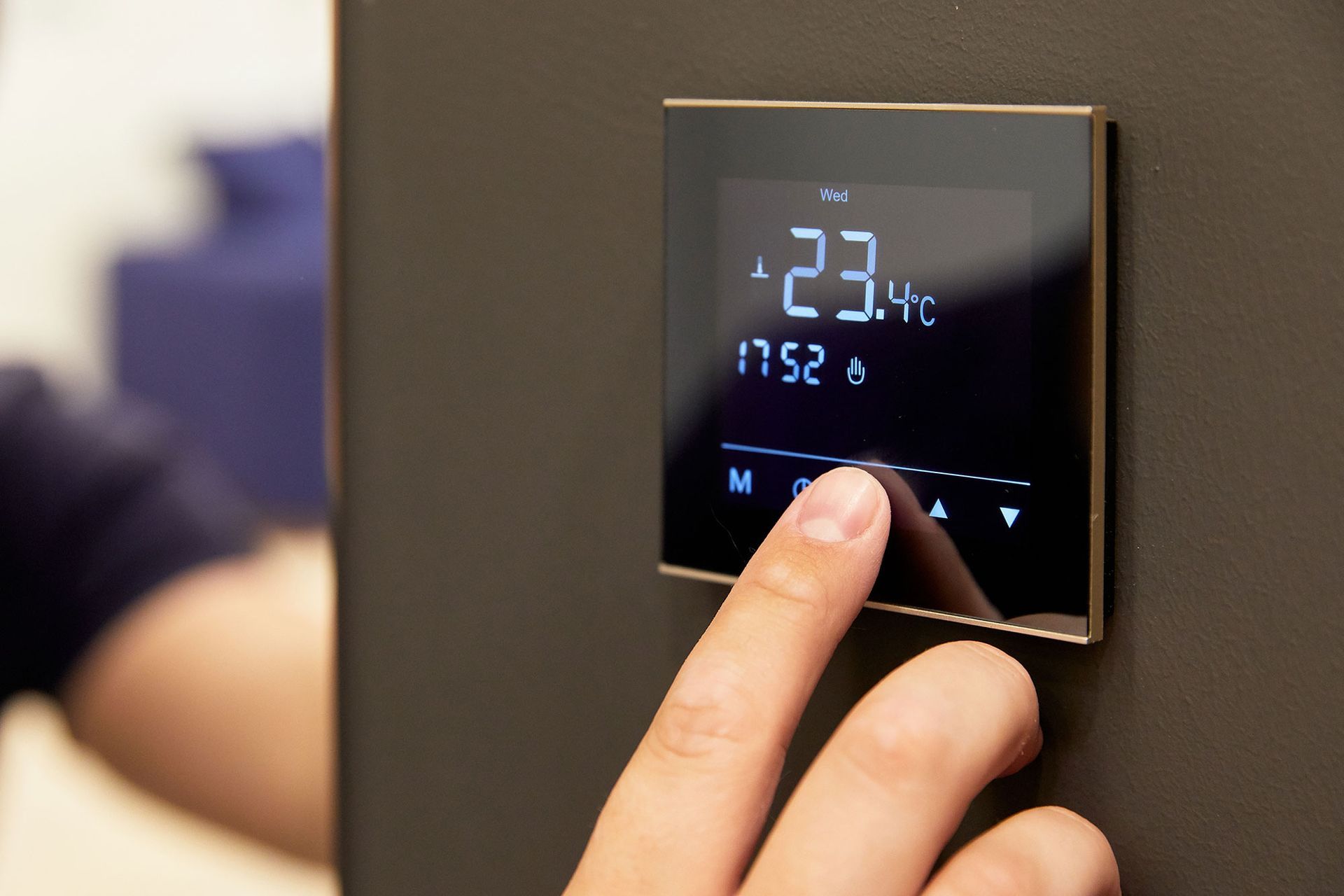 A person is adjusting the temperature on a touch-screen thermostat