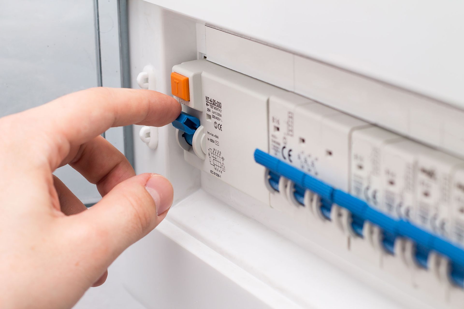 A person is flicking a switch on an electrical fuse box.