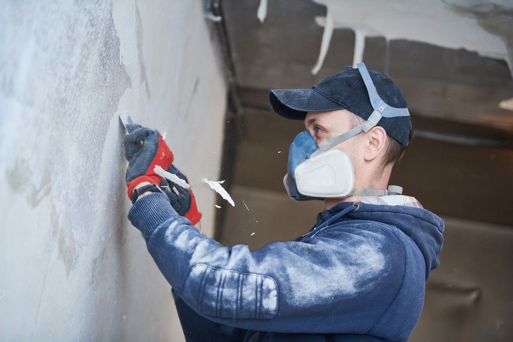 Professional restoration workers carefully remove damaged paint layer in a fire-damaged indoor interior.