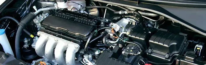 A high-angle view of a clean car engine bay, showing the engine block, silver intake manifold, and various components.
