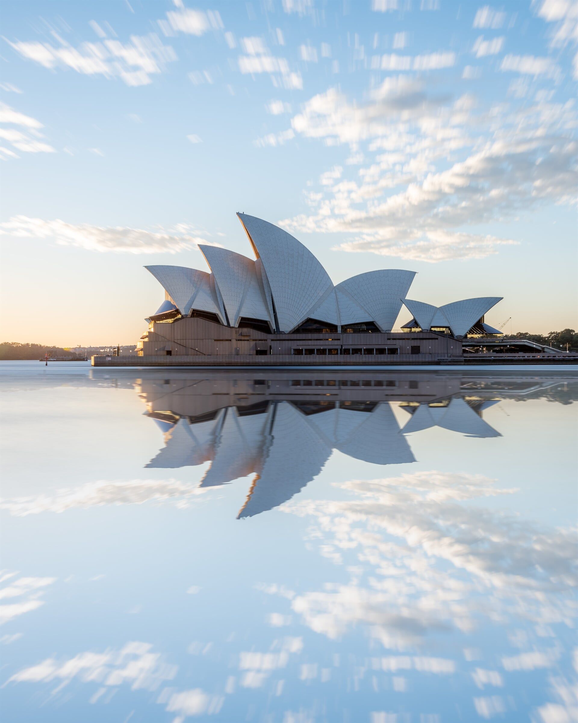 The opera house in sydney is reflected in the water.