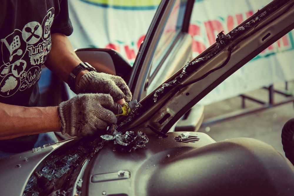 A Man Wearing Gloves is Working on a Car — Southern Tablelands Windscreen Repairs In Bowral, NSW