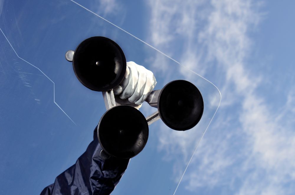 A Person is Holding Two Suction Cups in Their Hand Against a Blue Sky — Southern Tablelands Windscreen Repairs In Southern Highlands, NSW