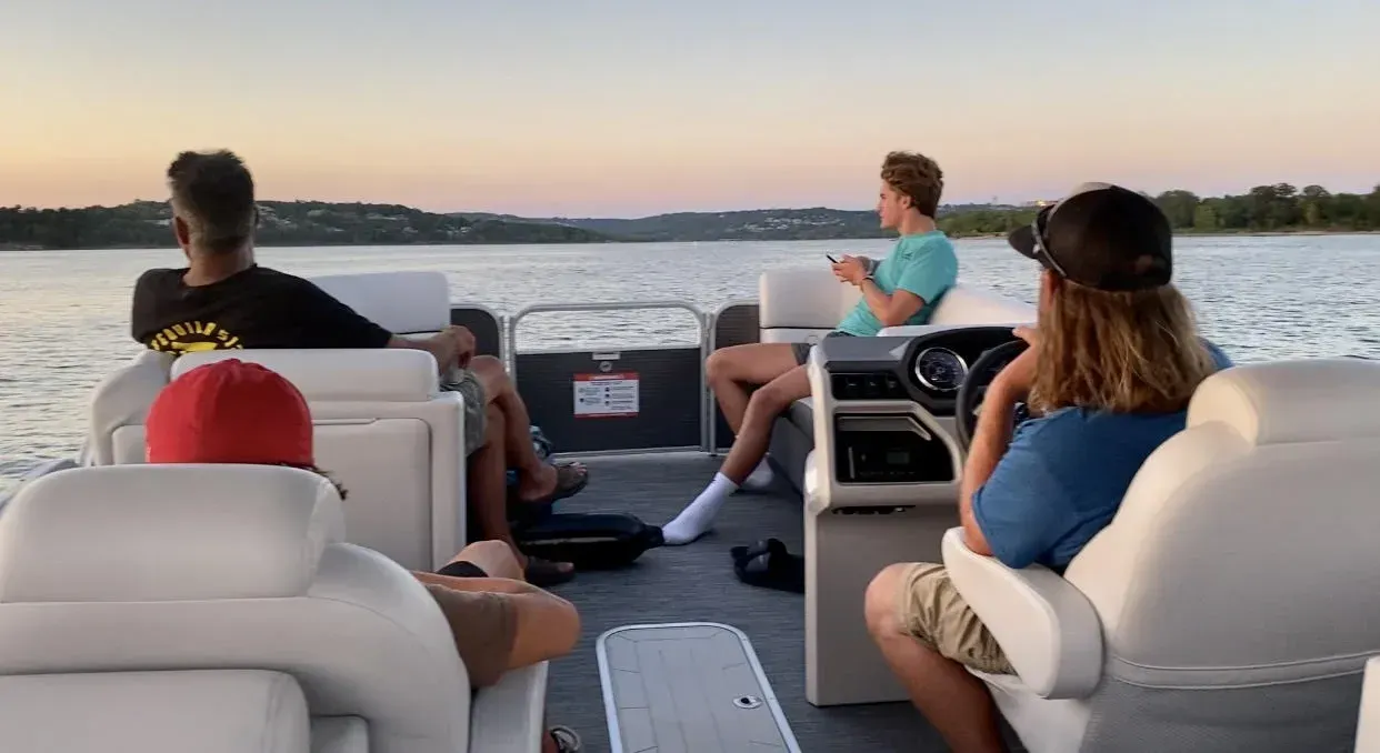 People on a pontoon boat on a lake. Passengers relaxing and enjoying the view at sunset.