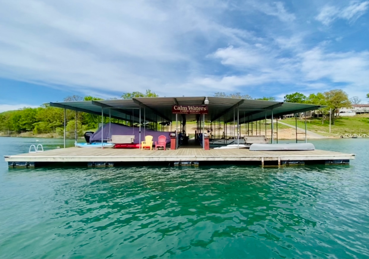 Dock on a lake with a covered seating area; water and trees in the background.