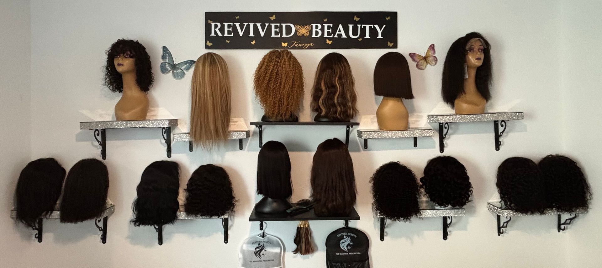 Wigs displayed on shelves with the sign Revived Beauty on a wall.