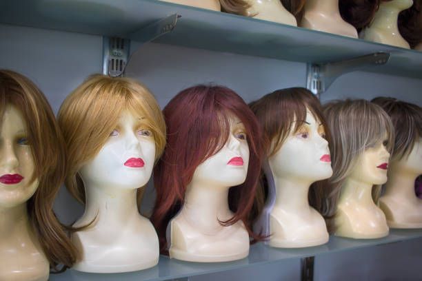 Row of mannequins with wigs in various colors on display shelves.