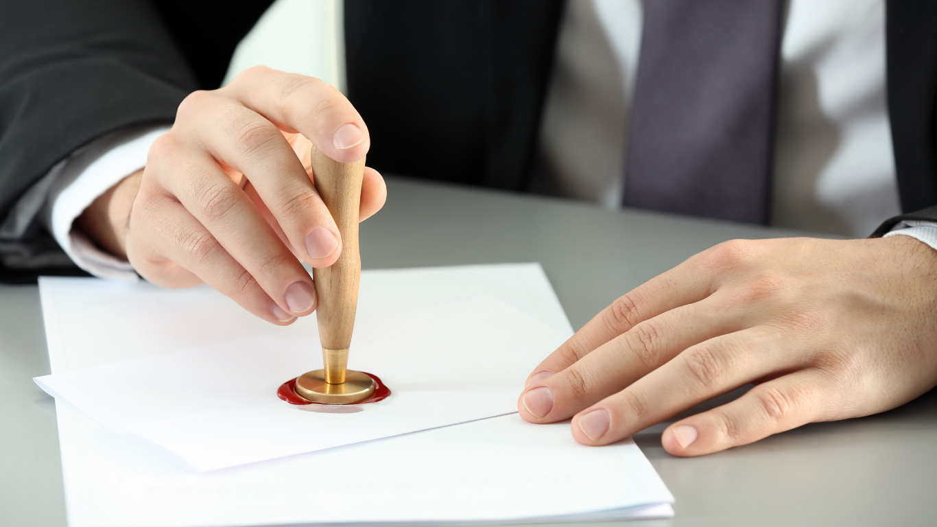 Person in suit seals envelope with a wax stamp.