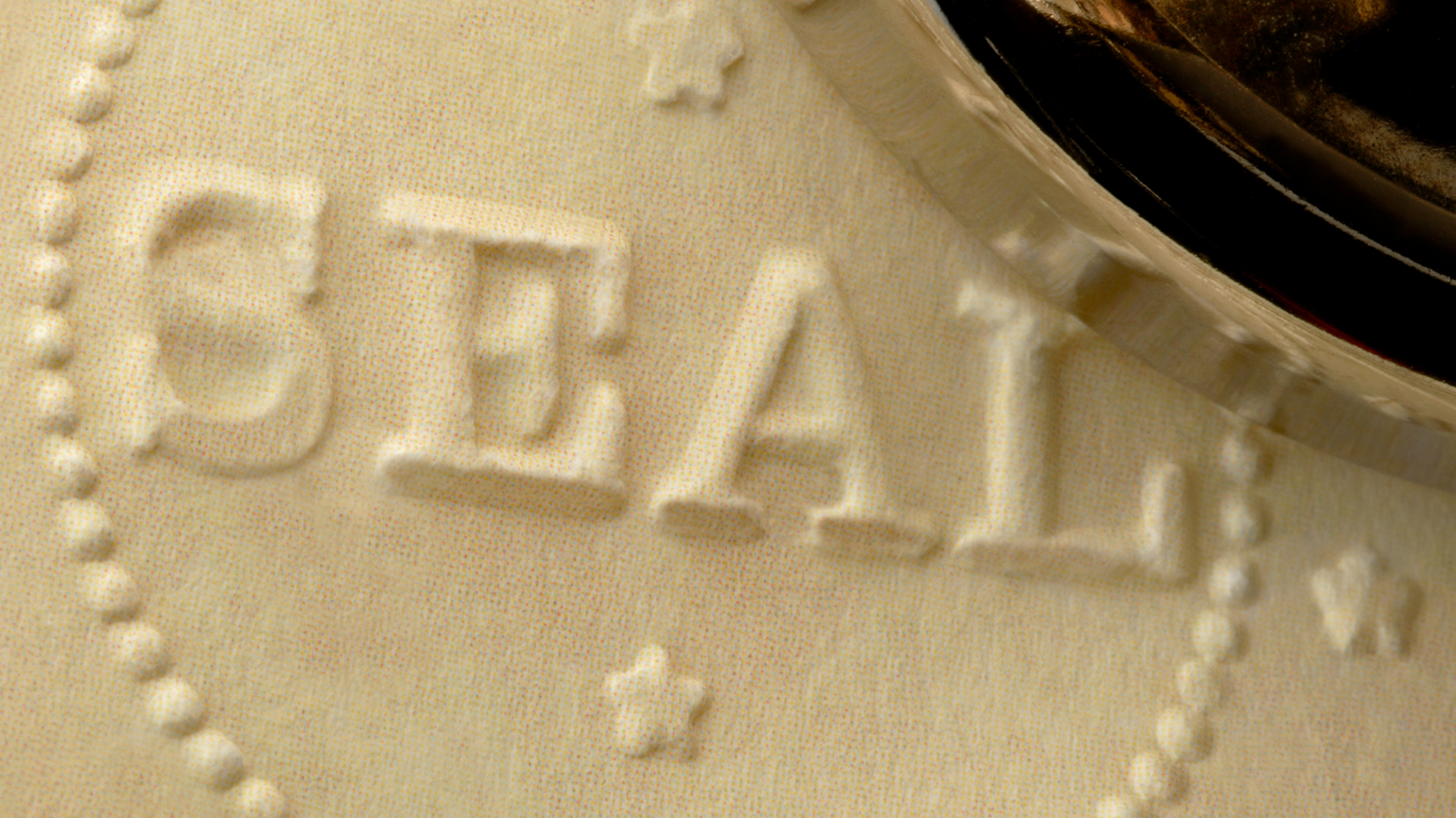 Person in suit signing a legal document with pen, next to a seal.