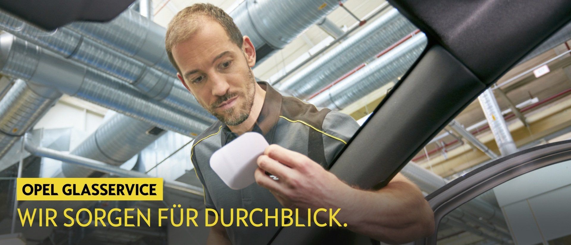 Ein Mann sitzt in einem Auto und schaut auf ein Blatt Papier.