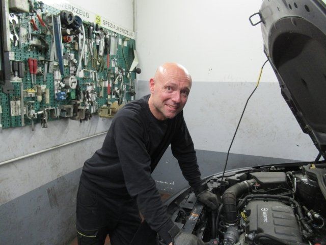 Ein Mann arbeitet an einem Auto mit geöffneter Motorhaube