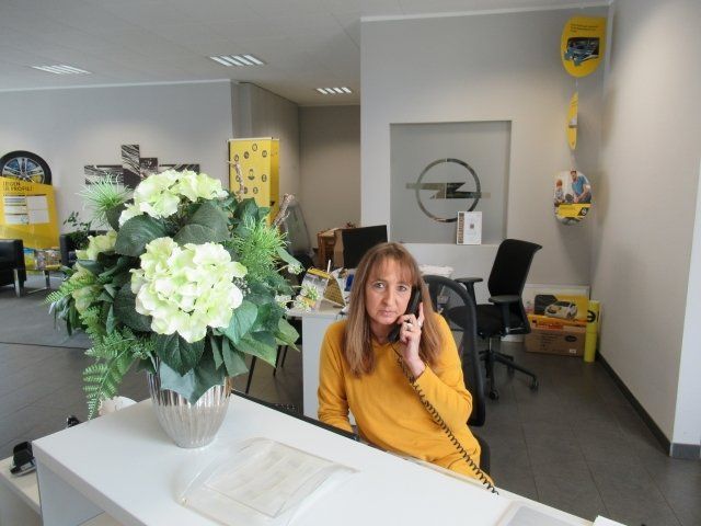 Eine Frau, die an einem Schreibtisch sitzt und mit einem Mobiltelefon telefoniert