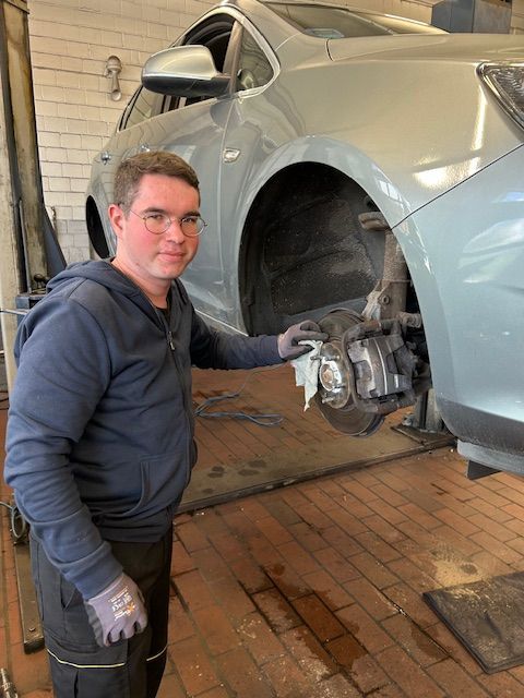 Ein Mann steht neben einem Auto in einer Garage.