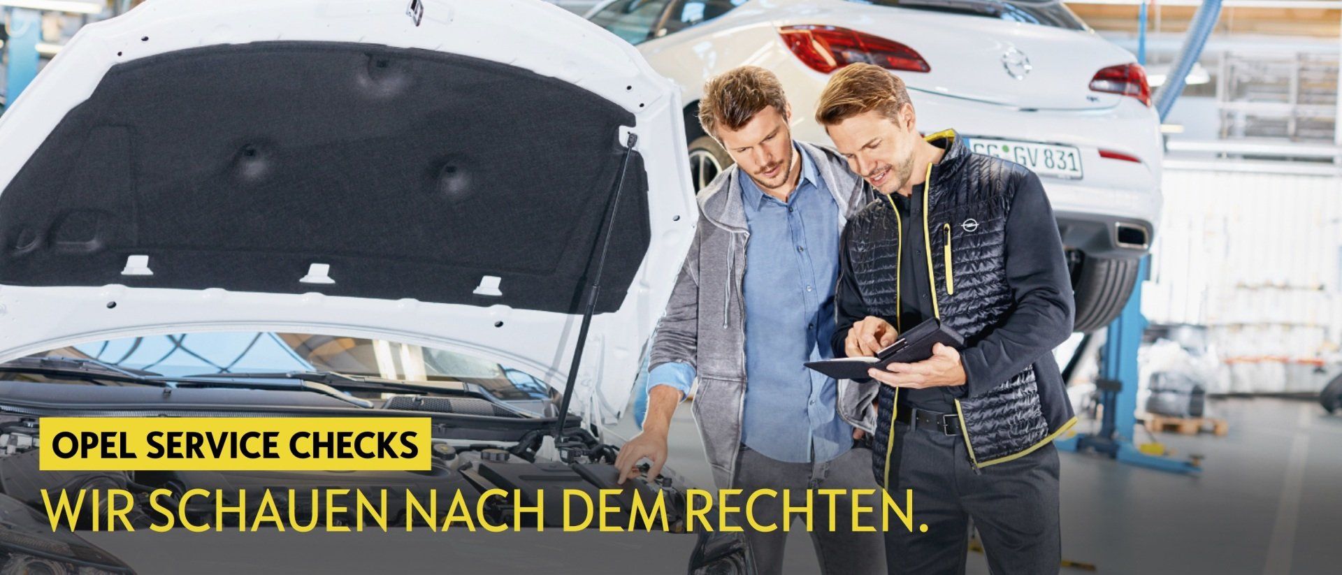 Zwei Männer schauen unter die Motorhaube eines Autos.