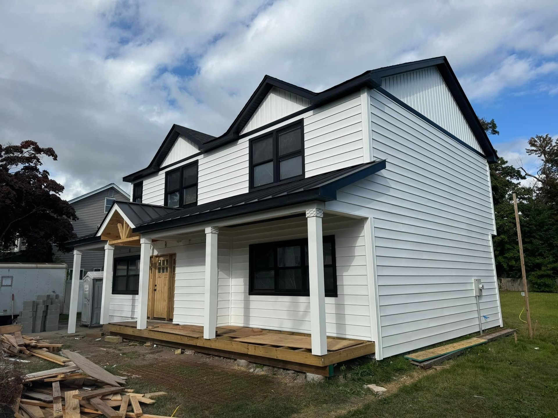 A white house with a black roof and a porch.