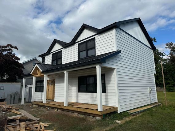 A white house with a black roof and a porch.