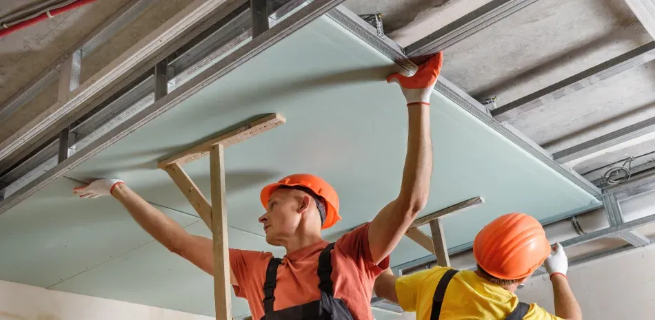 A couple of men are working on a ceiling.