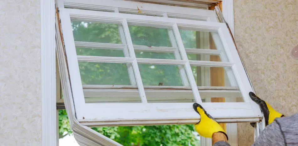 A man is installing a window in a house.