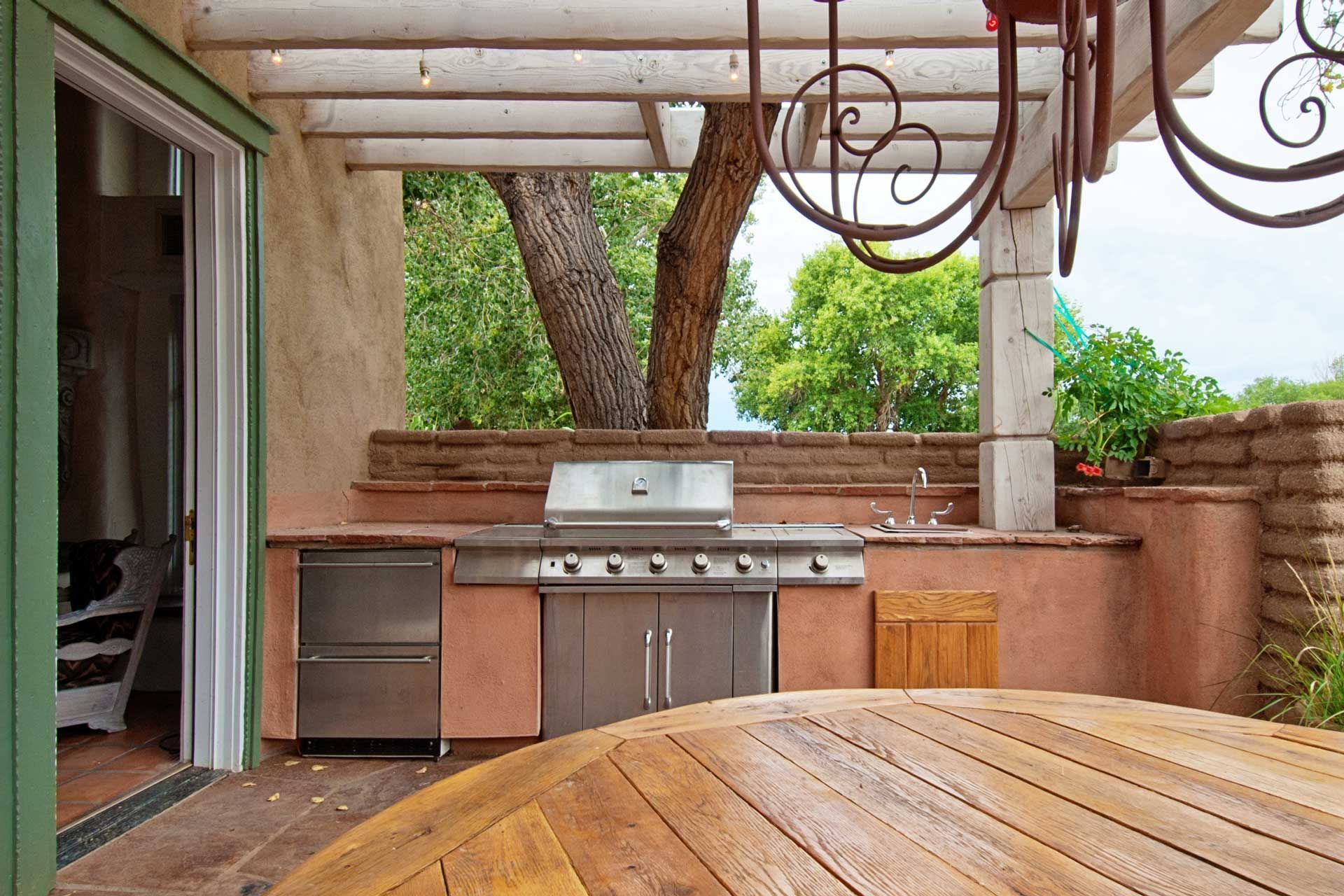 An outdoor kitchen with a grill and a wooden table