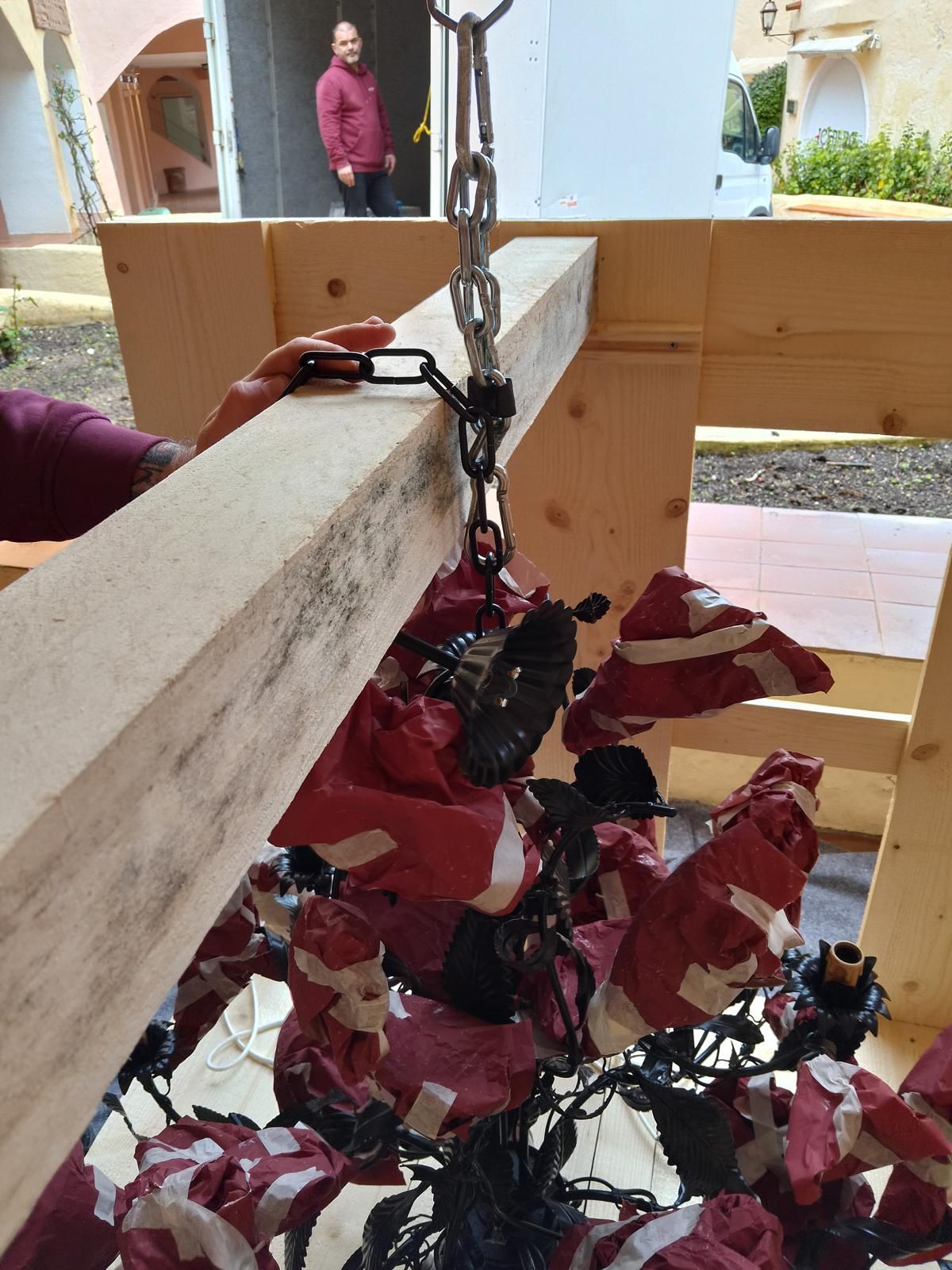 Persona che fissa un oggetto simile a un lampadario a una cornice di legno. Un'altra persona sullo sfondo.