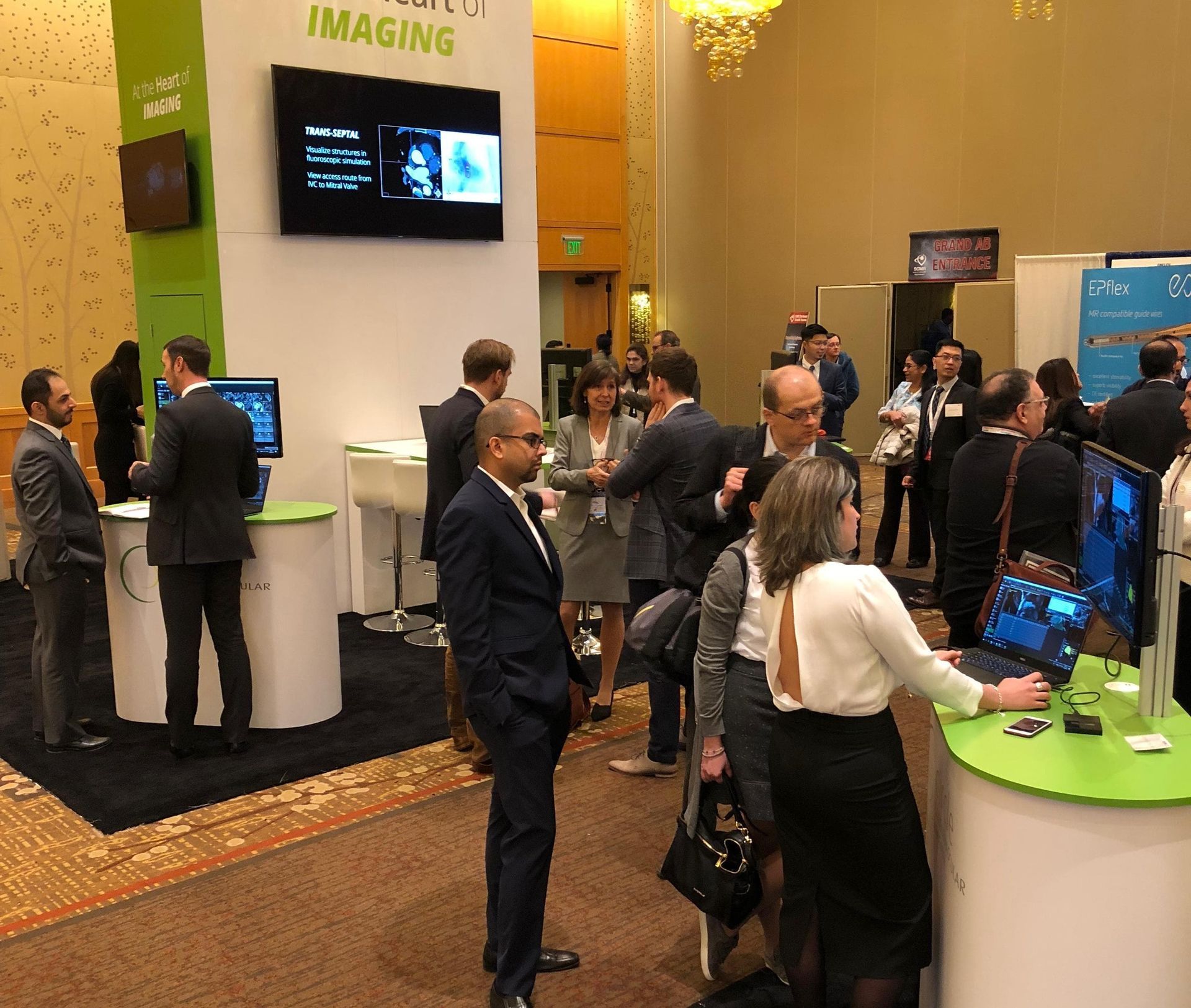 Conference attendees at booths, some looking at computer screens.