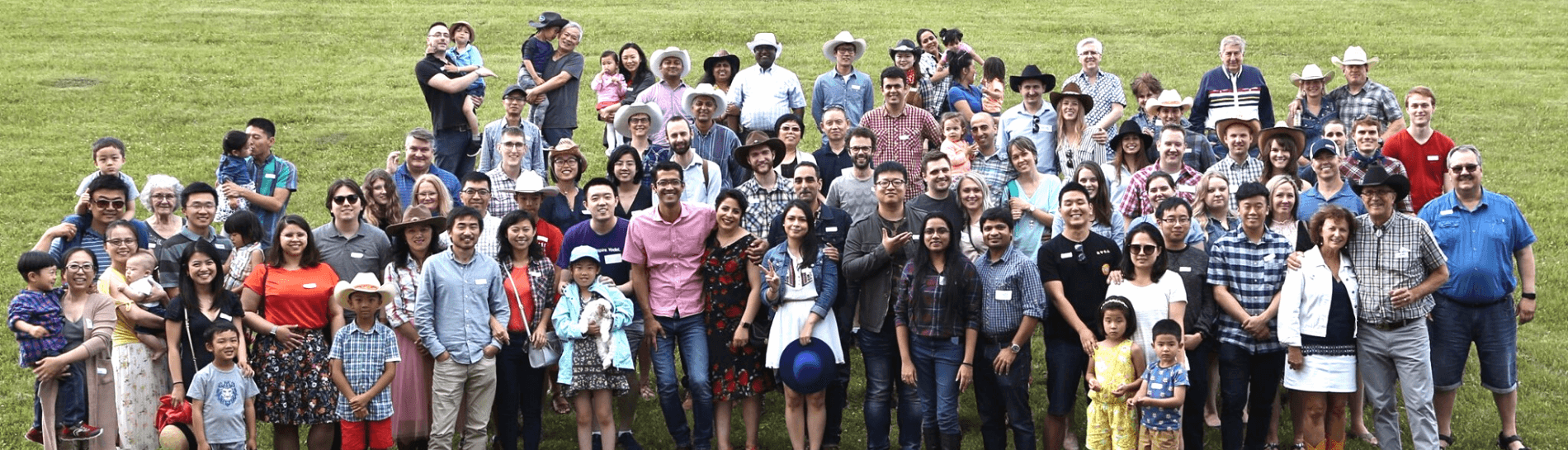 Group of people posing together on a grassy field.