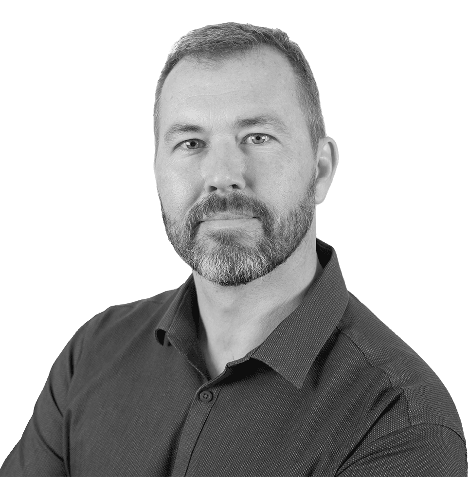 Man with a beard and short hair wearing a dark button-down shirt, looking directly at the viewer.