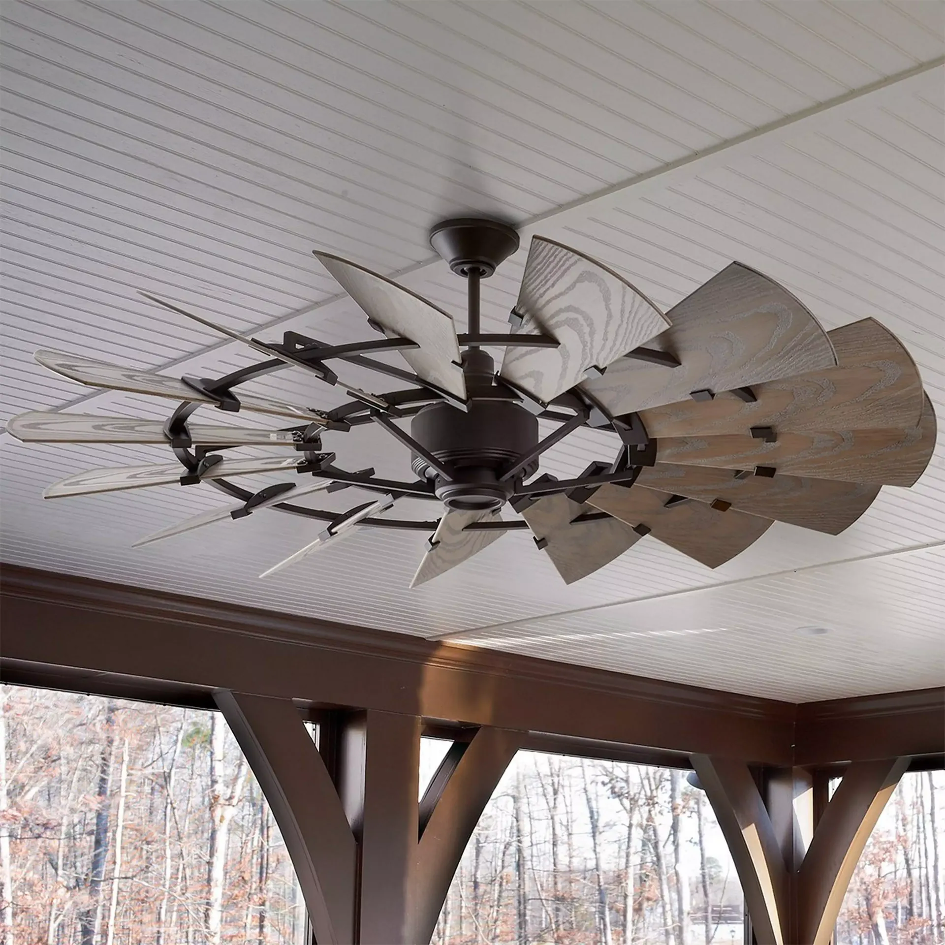 Ceiling fan with wooden blades, dark metal frame, installed on a porch ceiling.