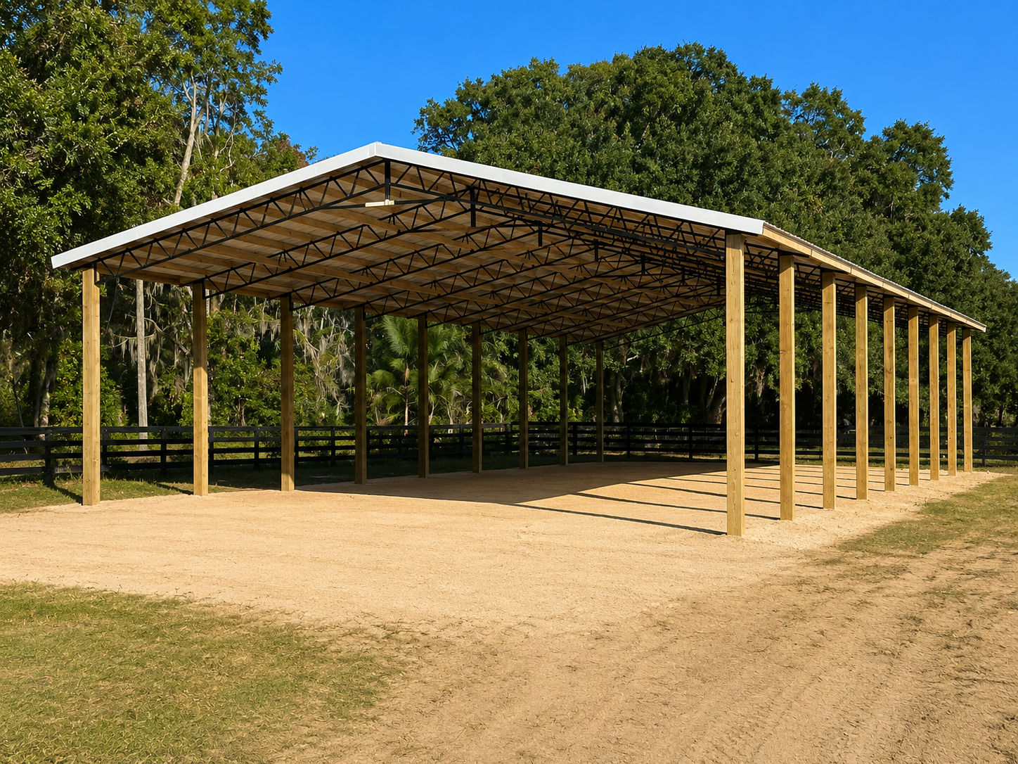 Open-air metal carport with wooden posts, in a dirt clearing with trees, under a blue sky.