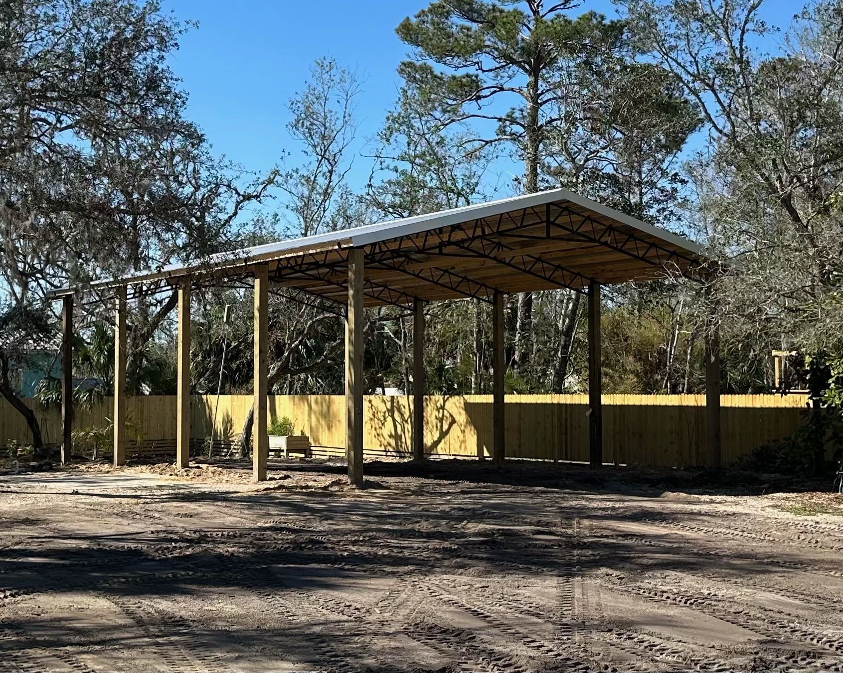 A newly built carport with a metal roof and wooden supports.