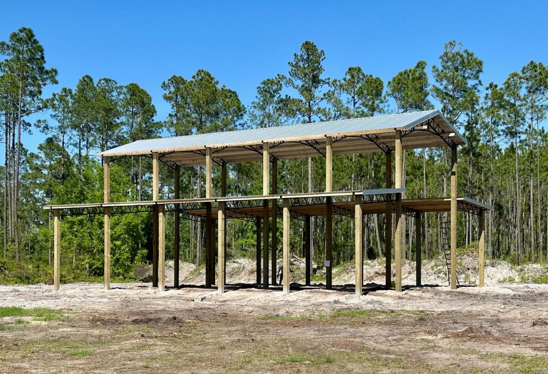 Two-story wooden structure with corrugated metal roof in a forest.