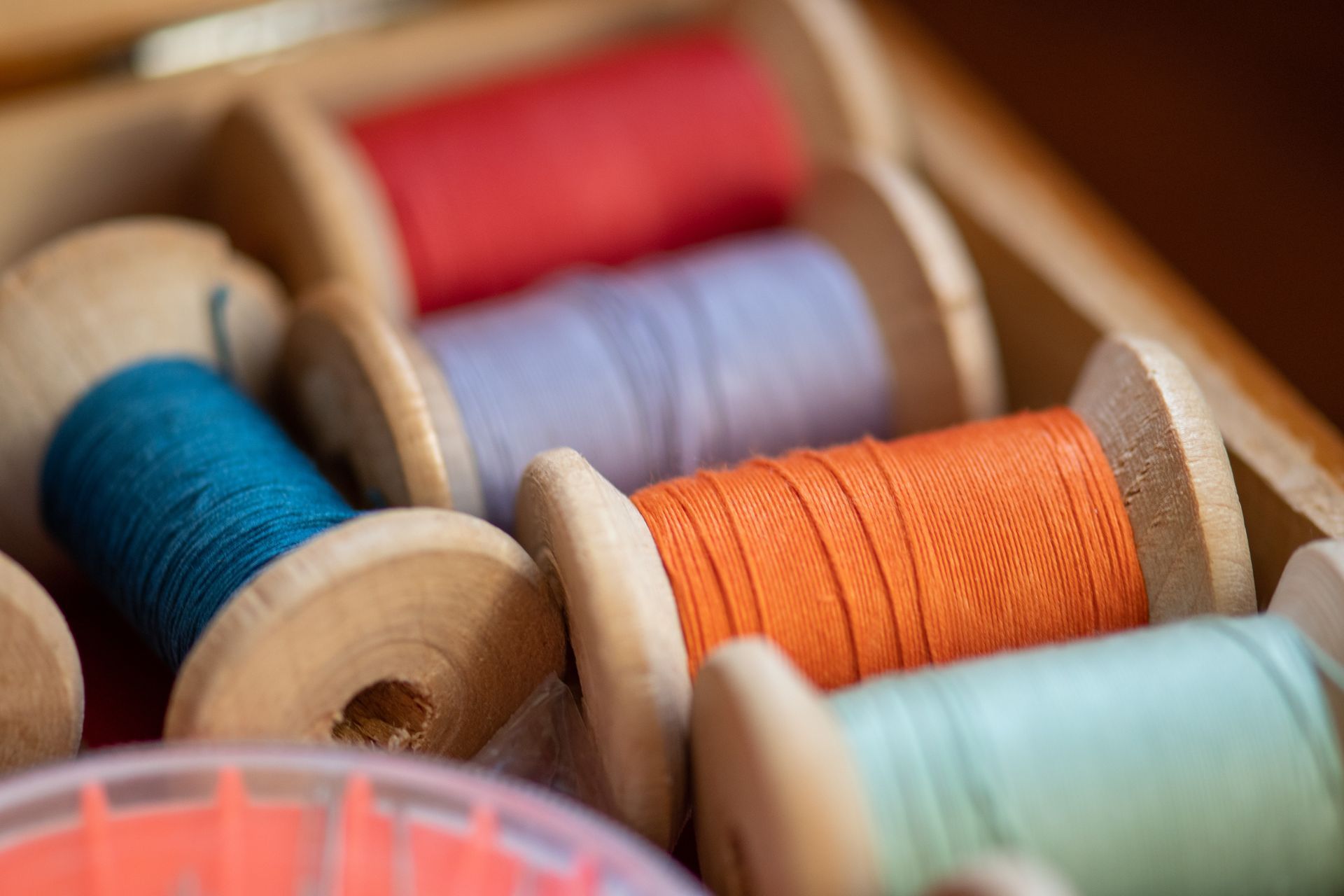 A wooden box filled with spools of thread of different colors.