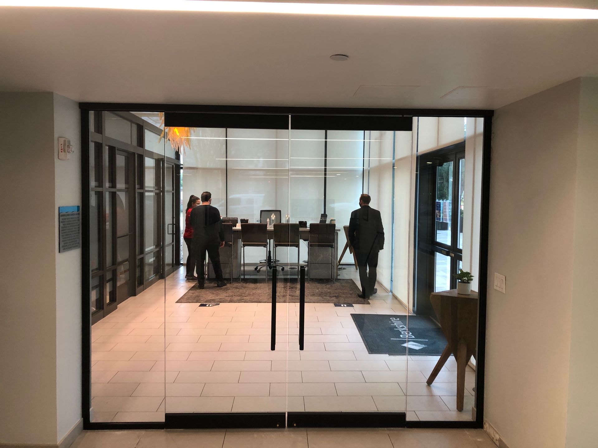 A group of people are standing in a room with a glass door.