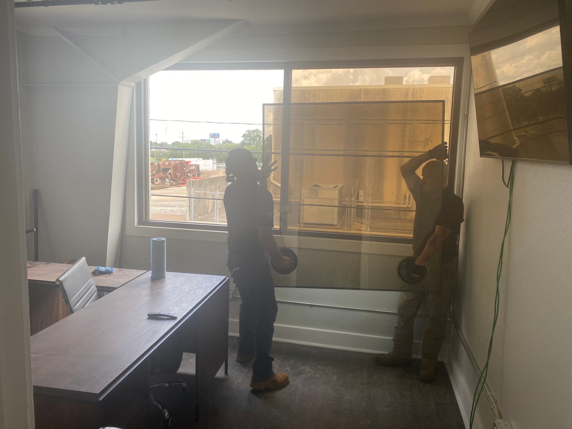 A man is standing in a room holding a glass window.